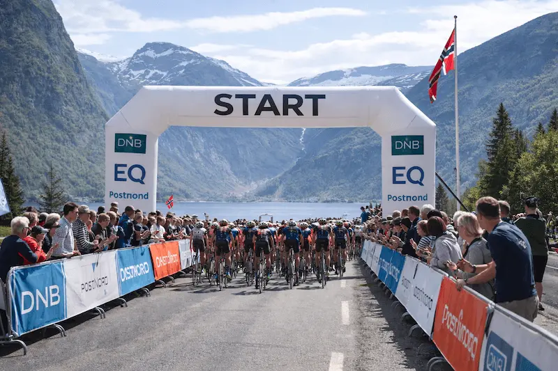 Gravel cyclists starting a race in Norwegian mountains with fjord landscape