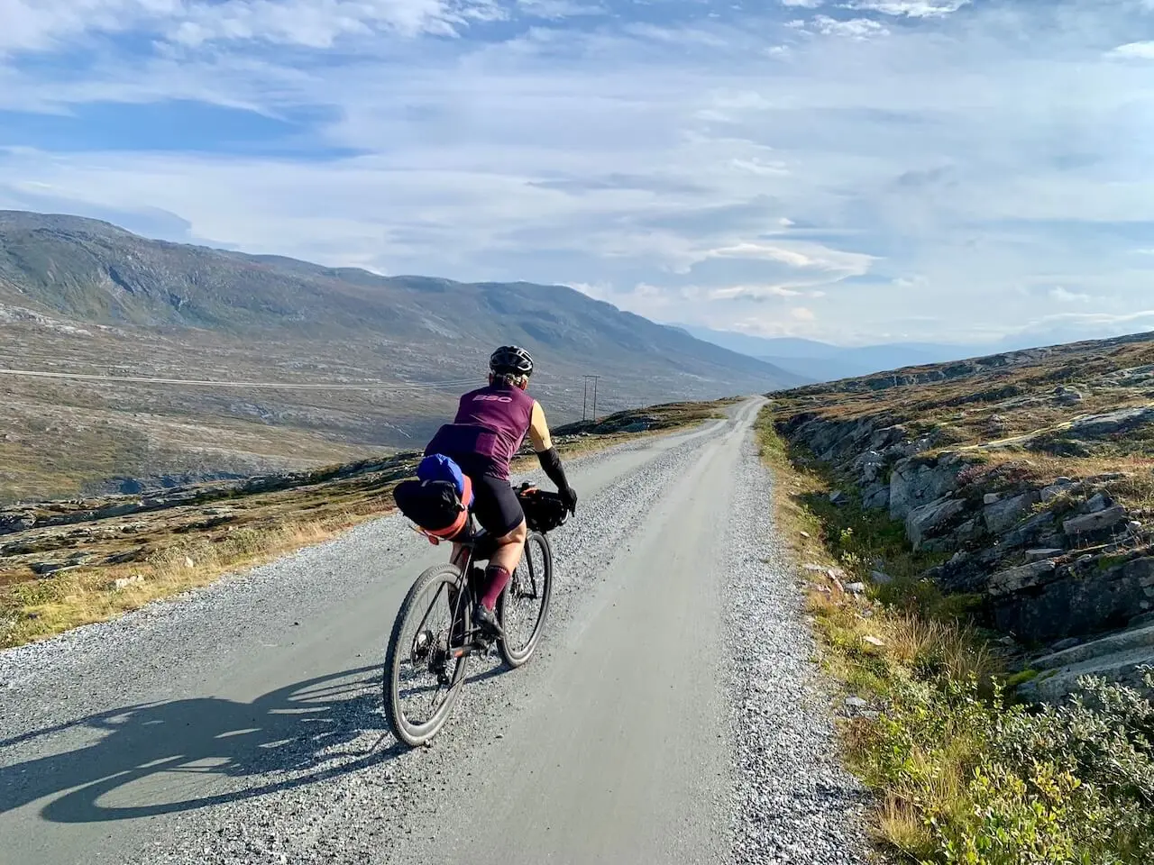 Cyclist riding on a gravel road through Norwegian mountains