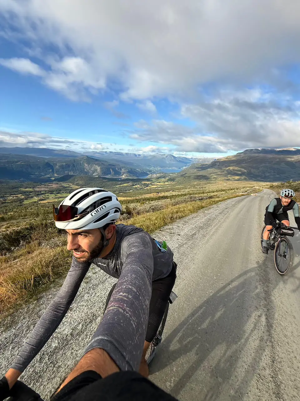 Two cyclists riding on a gravel road in the mountains